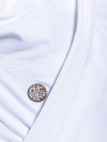 Close-up of the SEKAI 3.0 BJJ Gi White Navy's textured white fabric, showcasing a stitched round patch with a gold and white design inspired by Asian calligraphy, characteristic of this martial arts uniform.